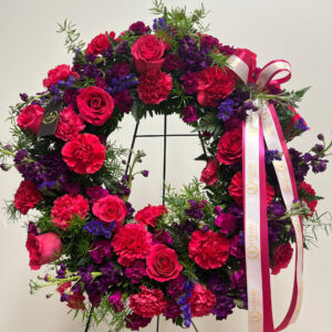 The Hot Pink & Purple Sympathy Wreath honors a loved one with roses, carnations, stock and statice, symbolizing love, remembrance and eternal peace.