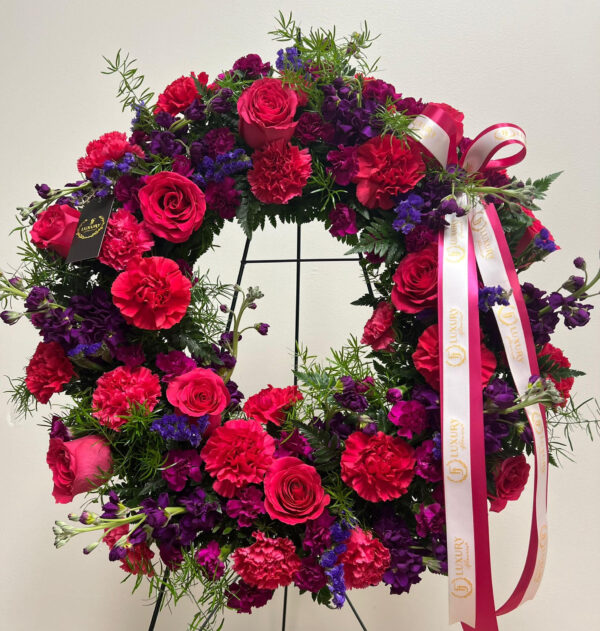 The Hot Pink & Purple Sympathy Wreath honors a loved one with roses, carnations, stock and statice, symbolizing love, remembrance and eternal peace.